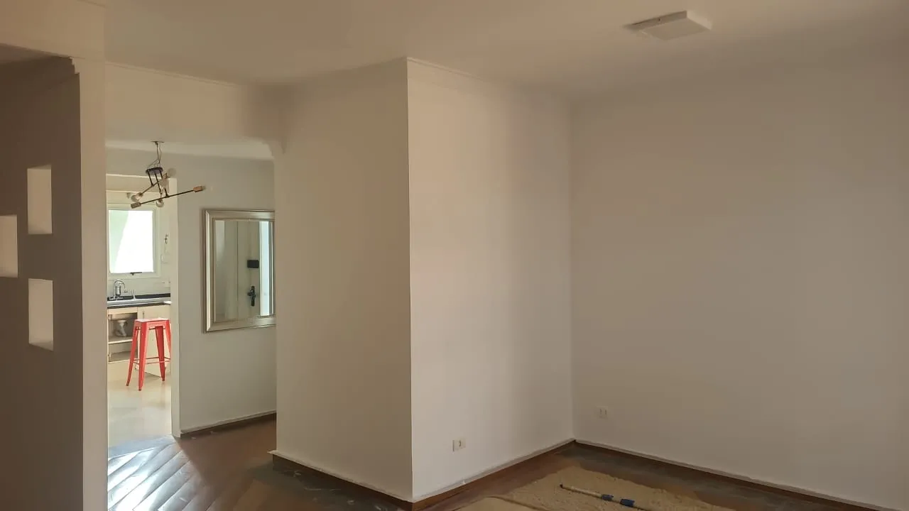 Sala de apartamento com paredes recém-pintadas de branco.